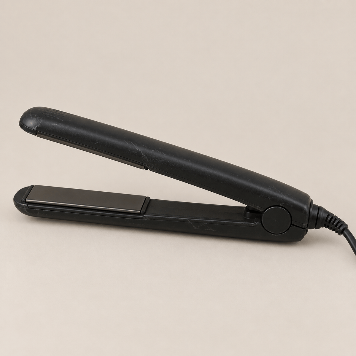Unbranded flat iron for comparison on a warm cream background.