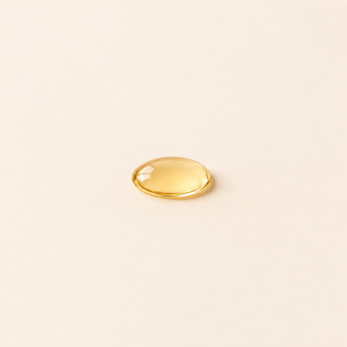 Golden argan oil droplet on a warm cream background.